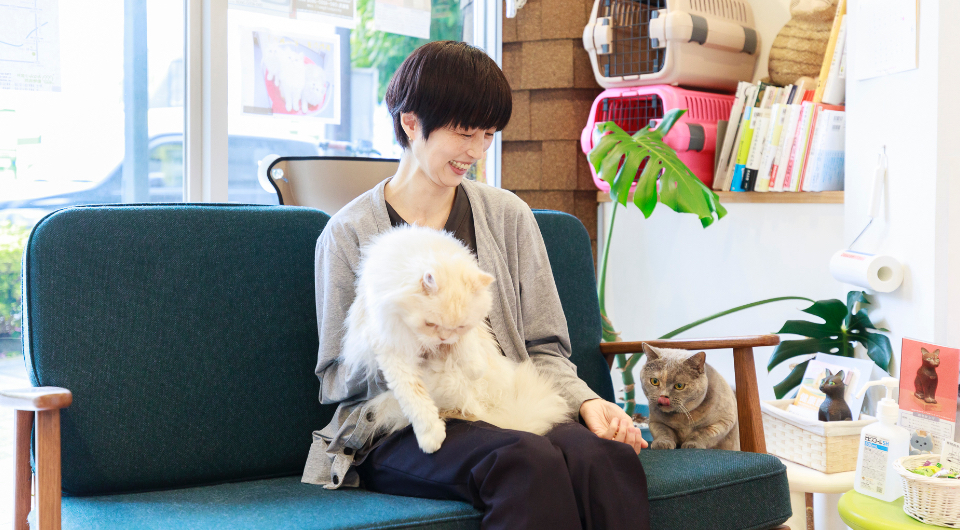 ソファーに座る女性と2頭の猫