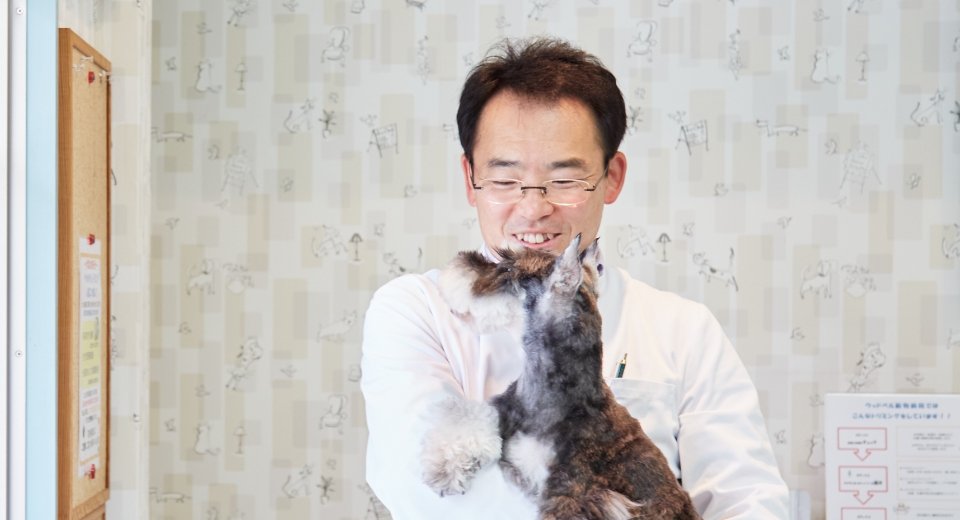 笑顔でシュナウザーを抱っこする獣医師の鈴木 快朗 先生